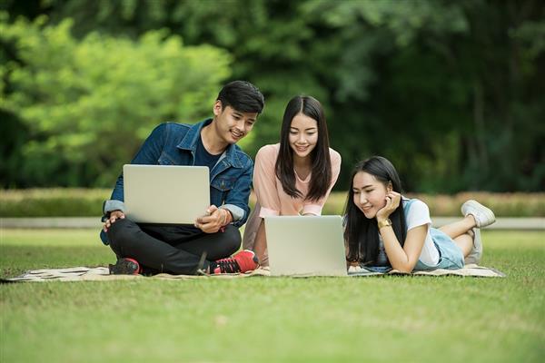 Students with computers on grass 